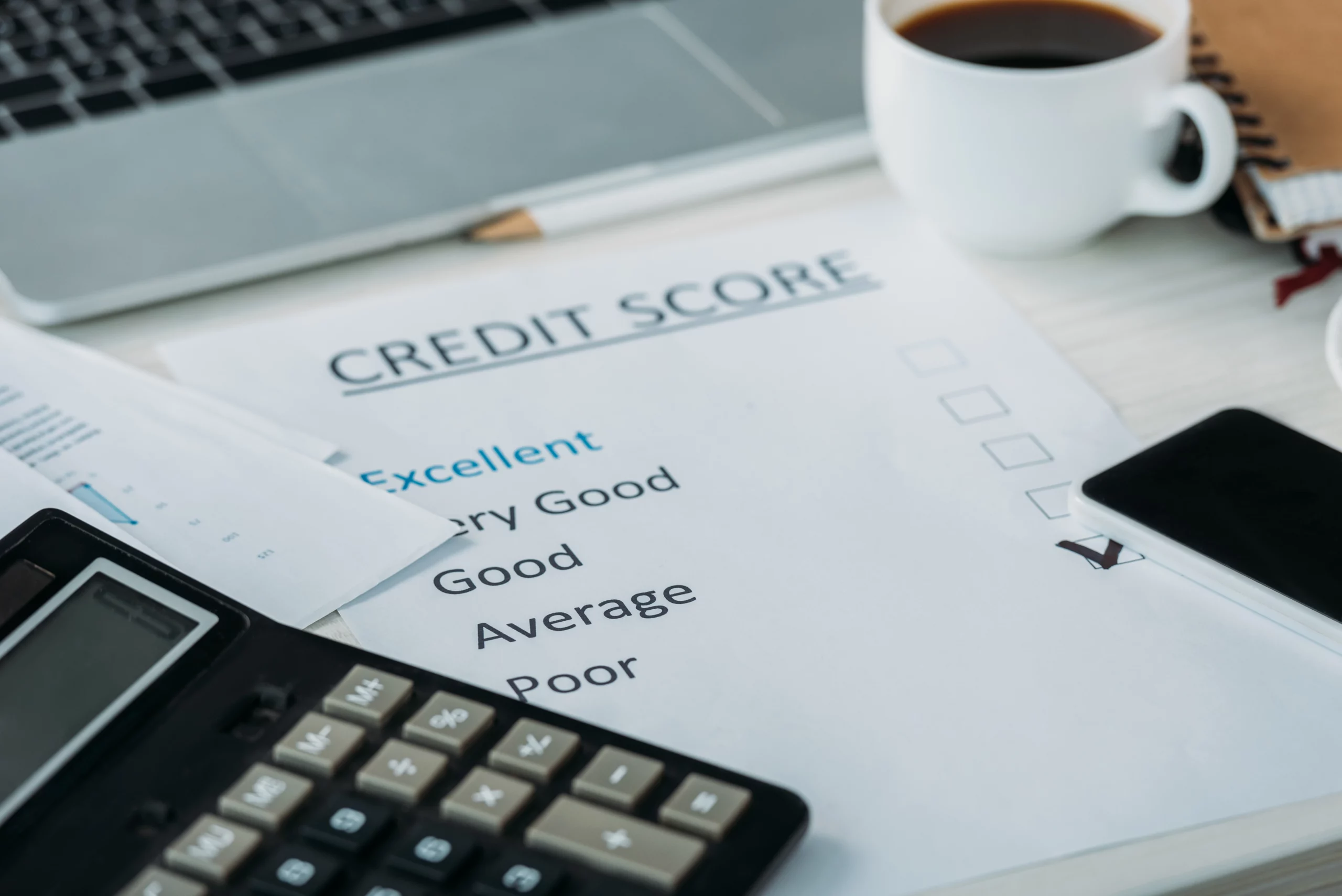 A credit score assessment form marked "Very Good" on a desk with a calculator, laptop, coffee cup, and smartphone, symbolizing financial recovery.