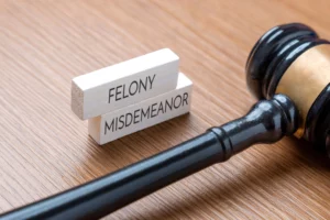 Judge’s gavel on a wooden table beside two wooden blocks labeled “felony” and “misdemeanor” — representing legal judgment, criminal charges and severity of crime in Washington State class‑C felony context.
